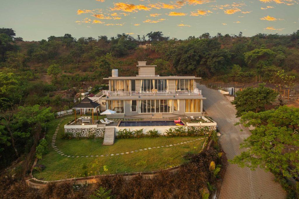 A large house with a pool in the middle of a forest.